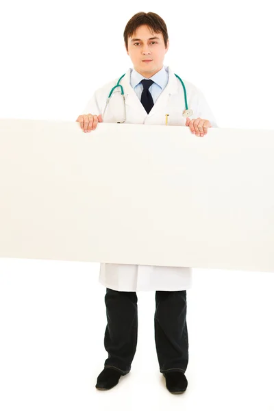 Serious medical doctor holding blank billboard — Stock Photo, Image