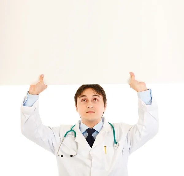 Medical doctor holding blank billboard over head — Stock Photo, Image