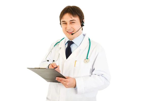 Leende läkare med headsetet håller Urklipp i hand — Stockfoto