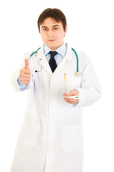 Lekarz, w ręku trzyma termometr lekarski i pokazuje kciuk w górę gest — Zdjęcie stockowe