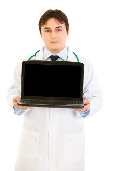 Ernsthafter Arzt hält Laptop mit leerem Bildschirm in der Hand — Stockfoto