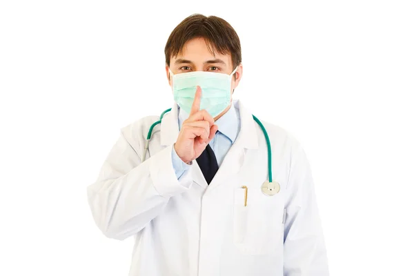 Medical doctor with mask on face holding finger at mouth. Shh gesture — Stock Photo, Image