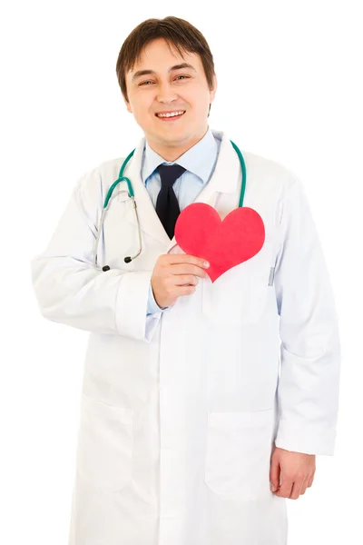 Médico sorridente segurando papel coração perto do peito — Fotografia de Stock