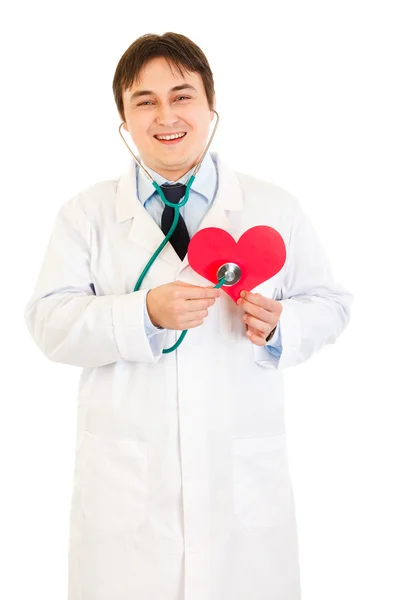Medico sorridente che tiene lo stetoscopio sul cuore di carta — Foto Stock
