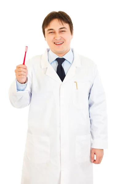 Dentista sonriente sosteniendo el cepillo de dientes en la mano — Foto de Stock