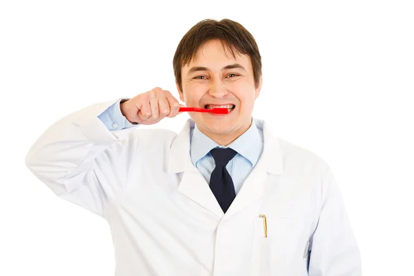 Усміхнений стоматолог зубною щіткою показує, як правильно чистити зуби — стокове фото