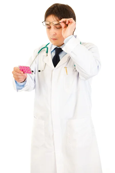 Koncentrerad läkare höja glasögon och läsa namnet på läkemedlet — Stockfoto