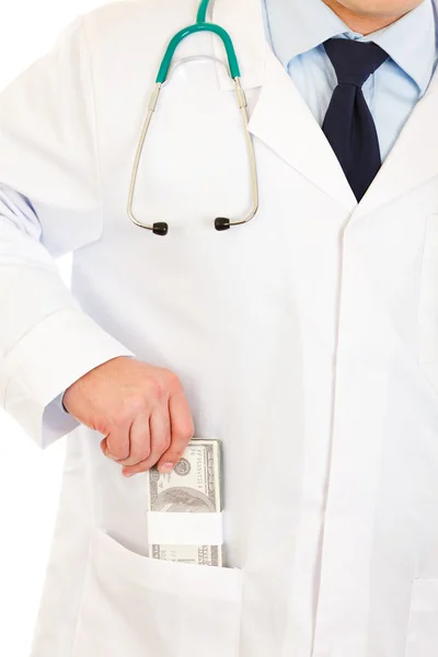 Médico poniendo dinero en la bata de bolsillo. Primer plano . — Foto de Stock
