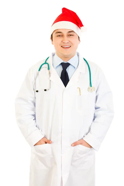 Glimlachend arts in Kerstman hoed zijn handen houden in zakken — Stockfoto