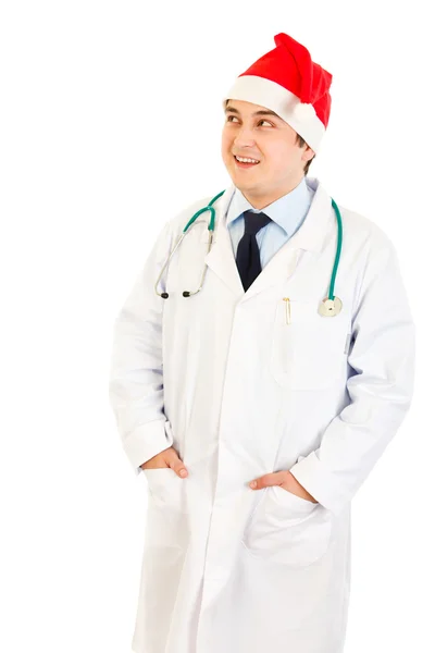 Smiling medical doctor in hat of Santa Claus looking up at copy space — Stock Photo, Image