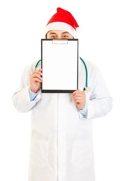 Medical doctor in Santa hat holding blank clipboard — Stock Photo, Image