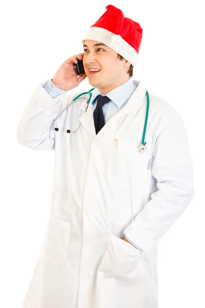 Smiling medical doctor in hat of Santa Claus talking on mobile phone — Stock Photo, Image