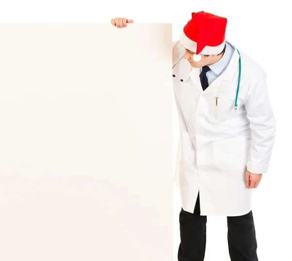 Ιατρός σε το καπέλο santa κοιτάζοντας κενό billboard — Φωτογραφία Αρχείου