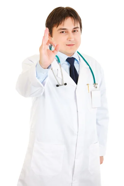 Leende unga läkare visar ok gest Royaltyfria Stockbilder