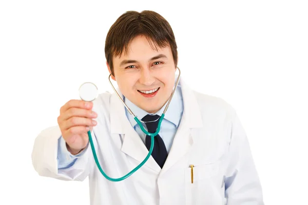 Lächelnder junger Arzt hält Stethoskop hoch Stockbild