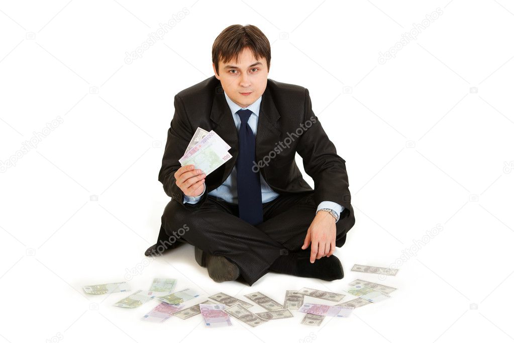 Successful businessman sitting surrounded by money and holding several bank