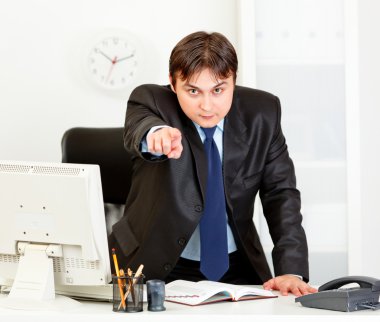 ofis masa başında duran ve işaret parmak üzerinde yo kızgın modern iş adamı