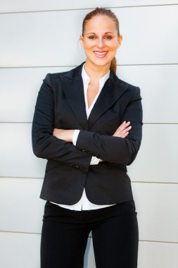 Smiling business woman with crossed arms on chest standing at office buildi clipart