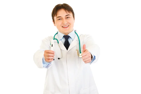 Médico sonriente sosteniendo termómetro médico y mostrando los pulgares hacia arriba gesto — Foto de Stock
