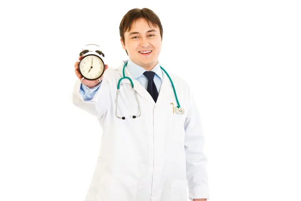 Улыбающийся врач держит будильник в руке — стоковое фото