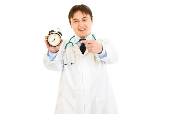 Médico sorridente apontando dedo no despertador — Fotografia de Stock