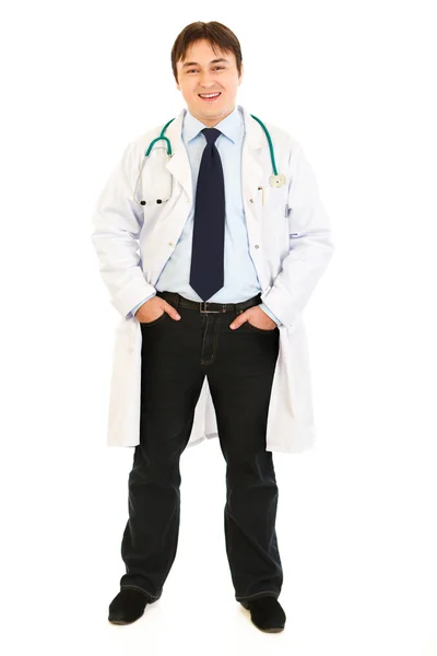 Médico sonriente con estetoscopio manteniendo las manos en los bolsillos —  Fotos de Stock