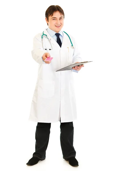 Médico sonriente sosteniendo portapapeles y medicamentos recetados en las manos —  Fotos de Stock