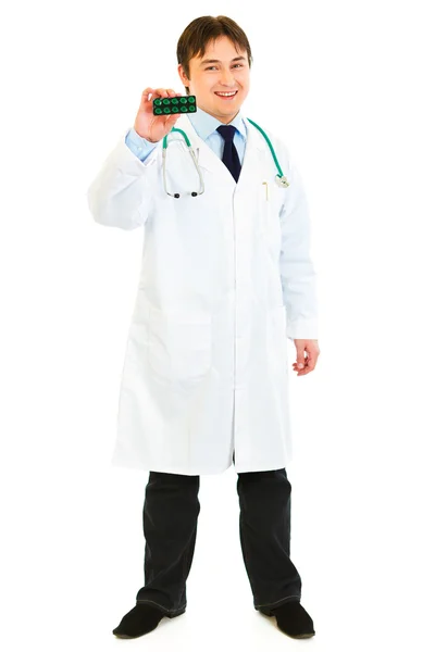 Полный портрет улыбающегося врача, демонстрирующего упаковку таблеток — стоковое фото