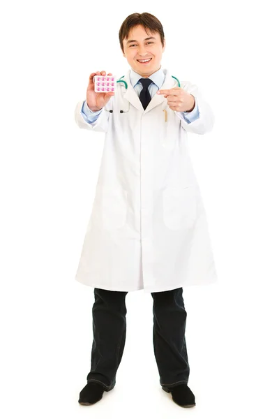 Uśmiechający się lekarzem, wskazując palcem na opakowanie tabletek — Zdjęcie stockowe