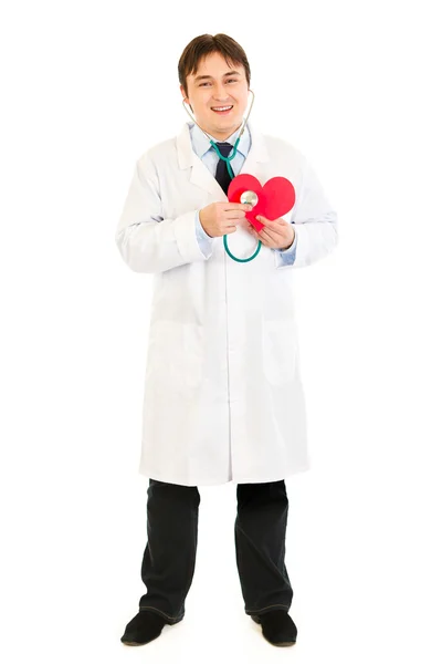 Улыбающийся доктор держит стетоскоп на бумажном сердце — стоковое фото