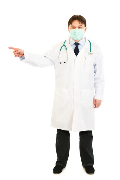 Medical doctor in mask pointing finger at something — Stock Photo, Image