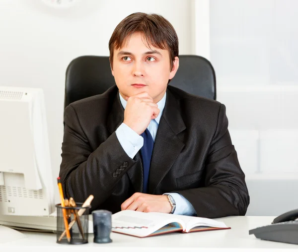 Jeune homme d'affaires pensif assis au bureau et planification horaire dans le journal — Photo