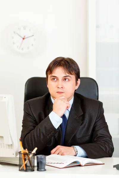 Fundersam ung affärsman sitter vid skrivbord och planering tidsplan i dagbok — Stockfoto