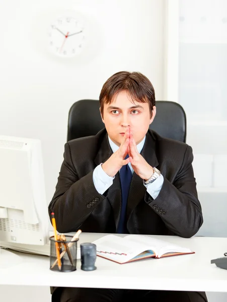 Pensive modern businessman sitting at desk in office — Stock Photo, Image