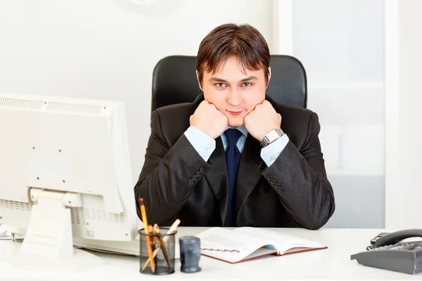 Бизнесмен сидит за рабочим столом и держит голову на руках — стоковое фото