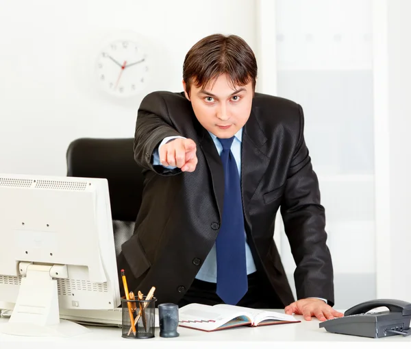Arg moderna affärsman står vid skrivbord och pekar finger på yo — Stockfoto