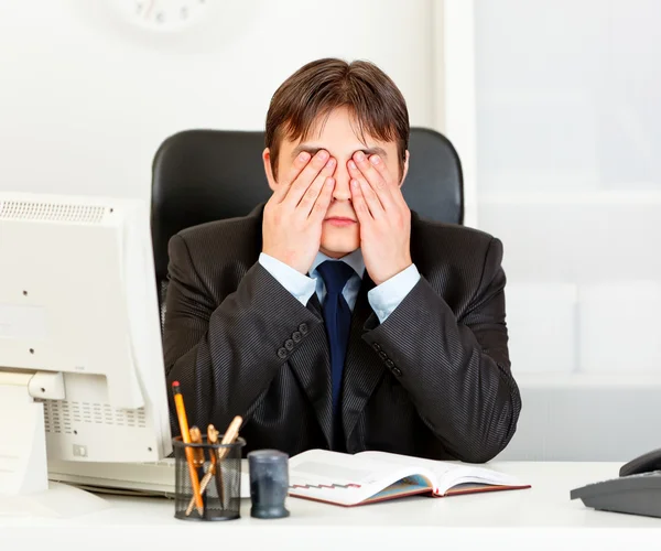 Modern businessman sitting at office desk and making see no evil gesture — Stock Photo, Image
