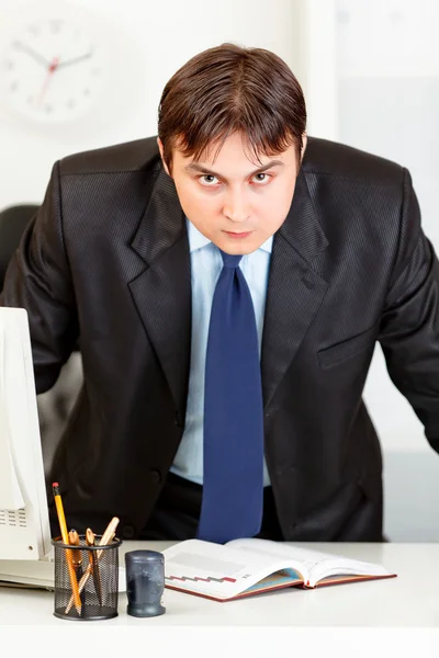 Uomo d'affari moderno rigoroso in piedi vicino alla scrivania dell'ufficio — Foto Stock