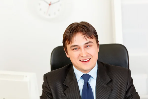 Χαμογελώντας σύγχρονο επιχειρηματία που κάθεται στο γραφείο — Φωτογραφία Αρχείου