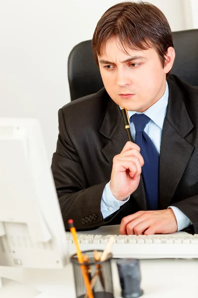 Pensativo hombre de negocios sentado en el escritorio de la oficina y mirando monit ordenador — Foto de Stock