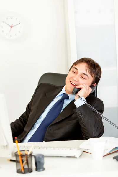 Agradable hombre de negocios moderno sentado en el escritorio de la oficina y hablando por teléfono — Foto de Stock