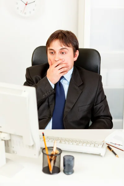 Geschokt zakenman aan bureau zitten en kijken naar monitor — Stockfoto