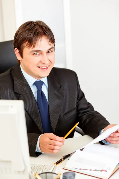 Hombre de negocios sonriente sentado en el escritorio de la oficina y trabajando con documentos — Foto de Stock