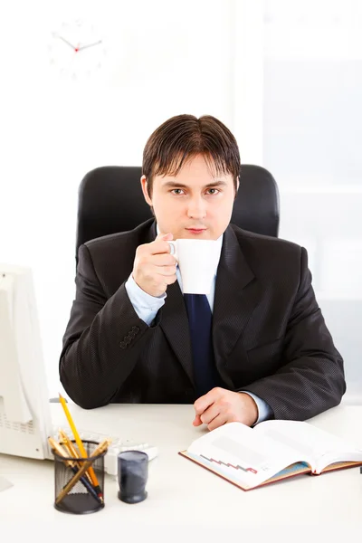 Uomo d'affari moderno seduto alla scrivania dell'ufficio e bere caffè — Foto Stock