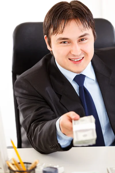 Uomo d'affari sorridente seduto alla scrivania dell'ufficio e dando pacchetto dollaro — Foto Stock