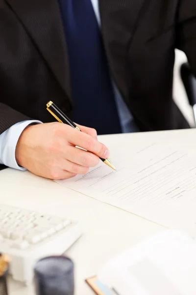 Businessman sitting at office desk and signing protocol. Close -up. — Stock Photo, Image