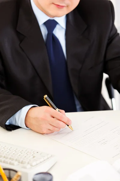 Бизнесмен сидит за рабочим столом и подписывает документы. Крупный план . — стоковое фото