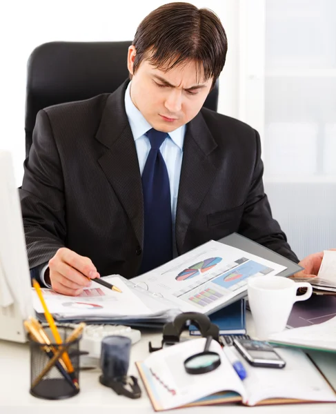 Thoughtful businessman sitting at office desk and working with financial d — Stock Photo, Image