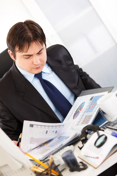 Empresário sério sentado na mesa do escritório e trabalhando com documentação financeira — Fotografia de Stock