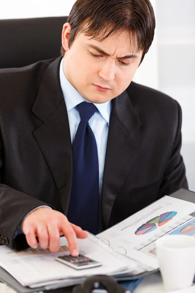 Seriös affärsman sitter vid office skrivbord och kontrollera ekonomisk rapport — Stockfoto